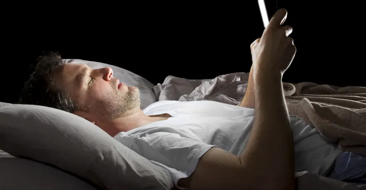 Man som surfar på en iPad i sängen