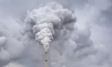 Smoke from factory pipe against dark overcast sky