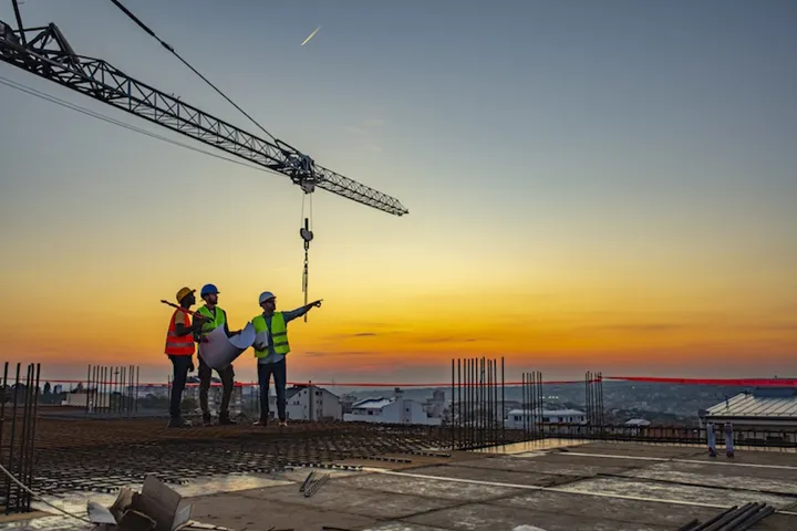 Multi ethic workers talking at construction site reviewing plans
