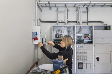 Kvinnlig elektriker jobbar vid elskåp