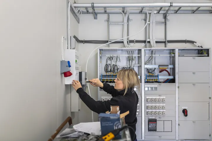 Kvinnlig elektriker jobbar vid elskåp