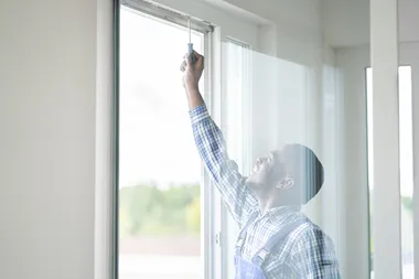 African Repairman In Overalls Installing Window