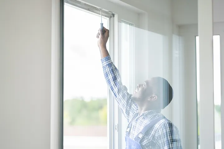 African Repairman In Overalls Installing Window
